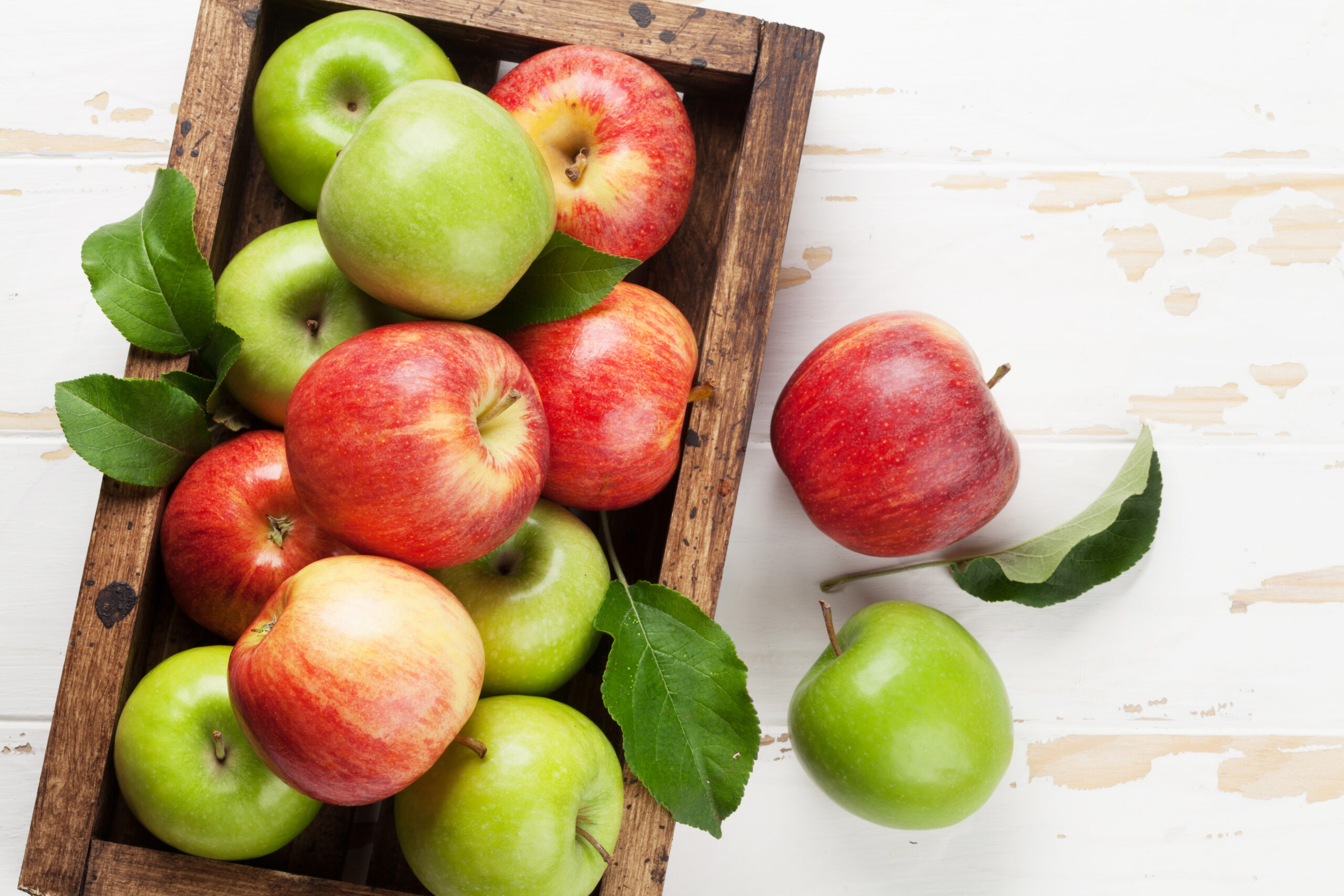 Green and red apples in wooden box